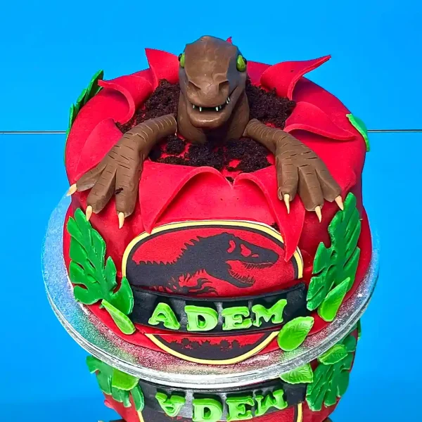 Gâteau sur mesure Jurassik Park avec dinosaures en 3D, idéal pour les anniversaires d'enfants à Genève et Lausanne. Création personnalisée avec détails réalistes et décorations comestibles.