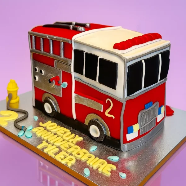 Gâteau en forme de camion de pompier 3D rouge, décoré de détails réalistes en pâte à sucre, création d’anniversaire enfant sur mesure à Genève ou Lausanne.