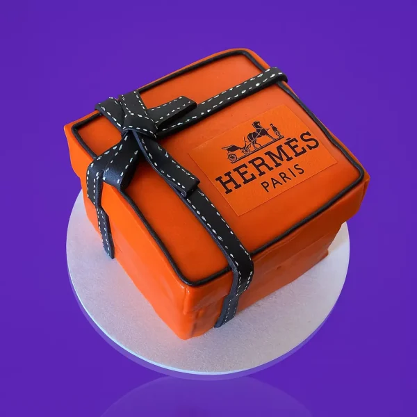Gâteau en forme de boîte Hermès orange avec ruban noir, design élégant inspiré du luxe et de la mode, gâteau personnalisé à Genève ou Lausanne.