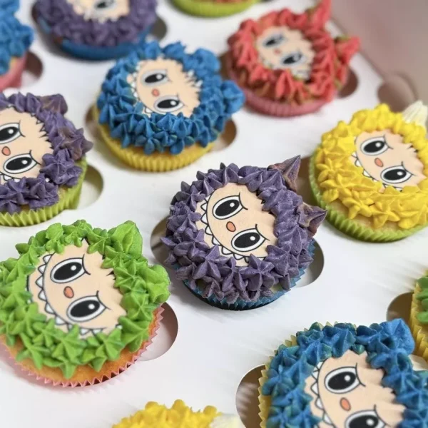 Cupcakes colorés décorés de visages kawaii style japonais, glaçage en crème multicolore, pâtisserie créative pour anniversaire ou fête à Genève ou Lausanne.