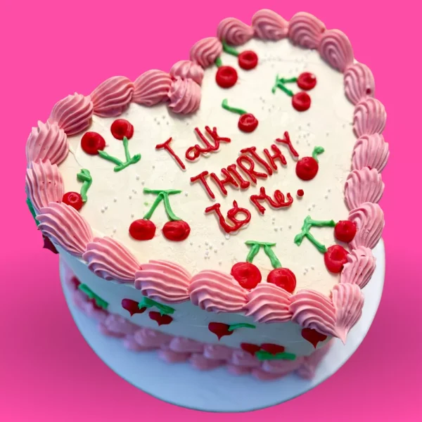 Gâteau vintage cœur avec glaçage rose, cerises décoratives et message personnalisé pour anniversaire, cake vintage sur mesure Genève Lausanne.