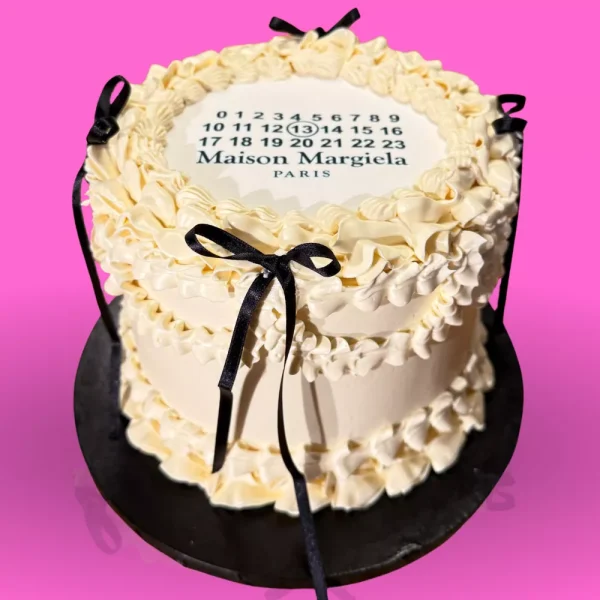 Gâteau vintage mode Maison Margiela avec crème blanche, rubans noirs et logo emblématique, cake chic personnalisé Genève Lausanne.